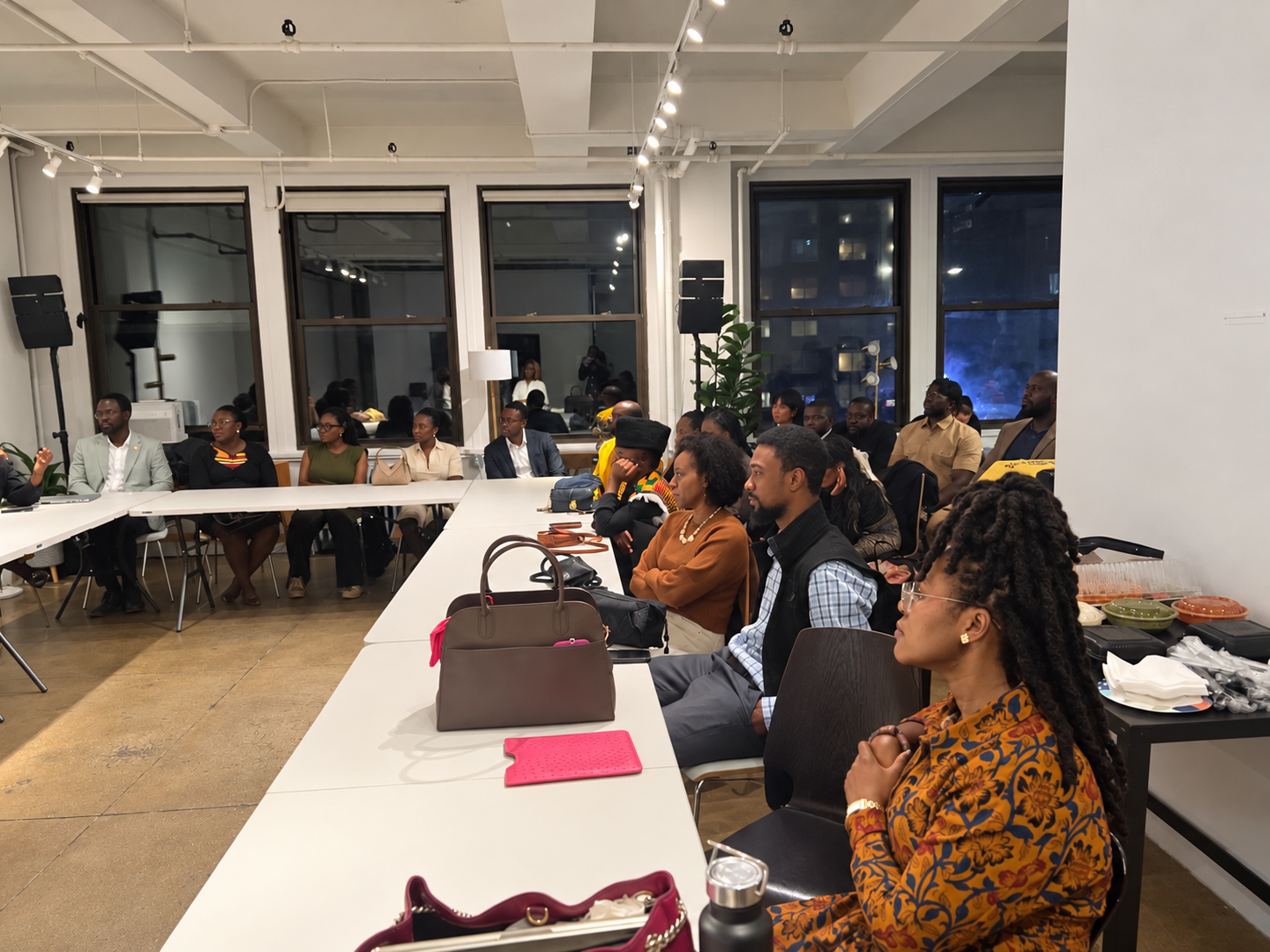 Attendees seated around long tables listening intently during a GHPAC business event in a loft venue